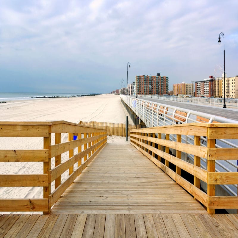 Long Beach boardwalk at golden hour, locals walking toward the ocean